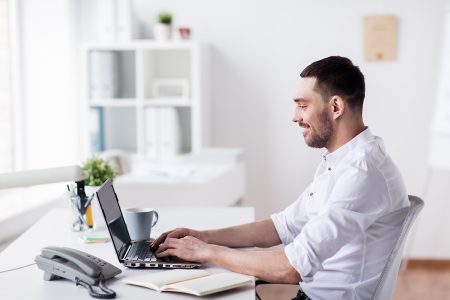 happy-businessman-with-laptop-at-office-P8J4GRH.jpg